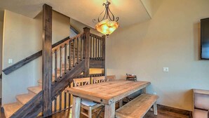 A wooden staircase with a chandelier, a dining table with benches, and a wall-mounted television. - Minutes from World Class Ski Resorts, Hot Tub! (Silverthorne)