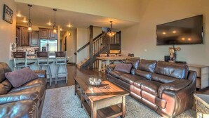 A spacious living room with a leather sofa, a coffee table, and a TV mounted on the wall. - Minutes from World Class Ski Resorts, Hot Tub! (Silverthorne)