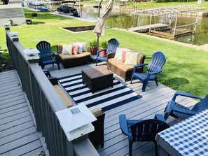 An outdoor deck with a seating area, including sofas and chairs, a table, and a small table with a white top.