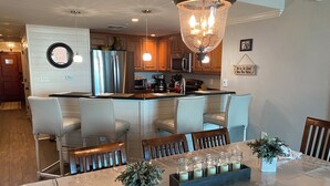A modern kitchen with a central island, a dining area with a table set for six, and a chandelier above. - North Myrtle Beach Absolutely stunning condo unit 615 on the sixth floor (North Myrtle Beach)
