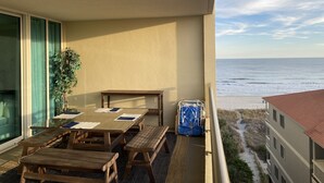 A balcony with a wooden table and benches, a potted plant, and a view of the beach and ocean. - North Myrtle Beach Absolutely stunning condo unit 615 on the sixth floor (North Myrtle Beach)