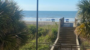 A wooden staircase leading to a beach with umbrellas and people. - North Myrtle Beach Absolutely stunning condo unit 615 on the sixth floor (North Myrtle Beach)