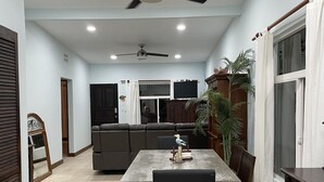 A spacious dining area with a table and chairs, a ceiling fan, and a view into a living room with a couch and a TV. - Private home with pool and only a block to the beach, restaurants, nightlife... (Jaco Beach)