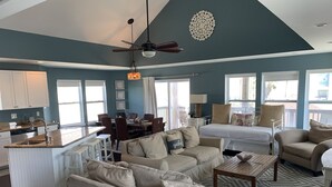 A spacious living area with a dining table, two sofas, a coffee table, and a kitchen area with a sink and counter. - Sunny Beach Luxurious House with View, Sleeps 12, Steps From Beach (Galveston)