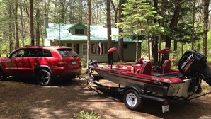 Un SUV rojo estacionado en un área boscosa con un remolque para embarcaciones.