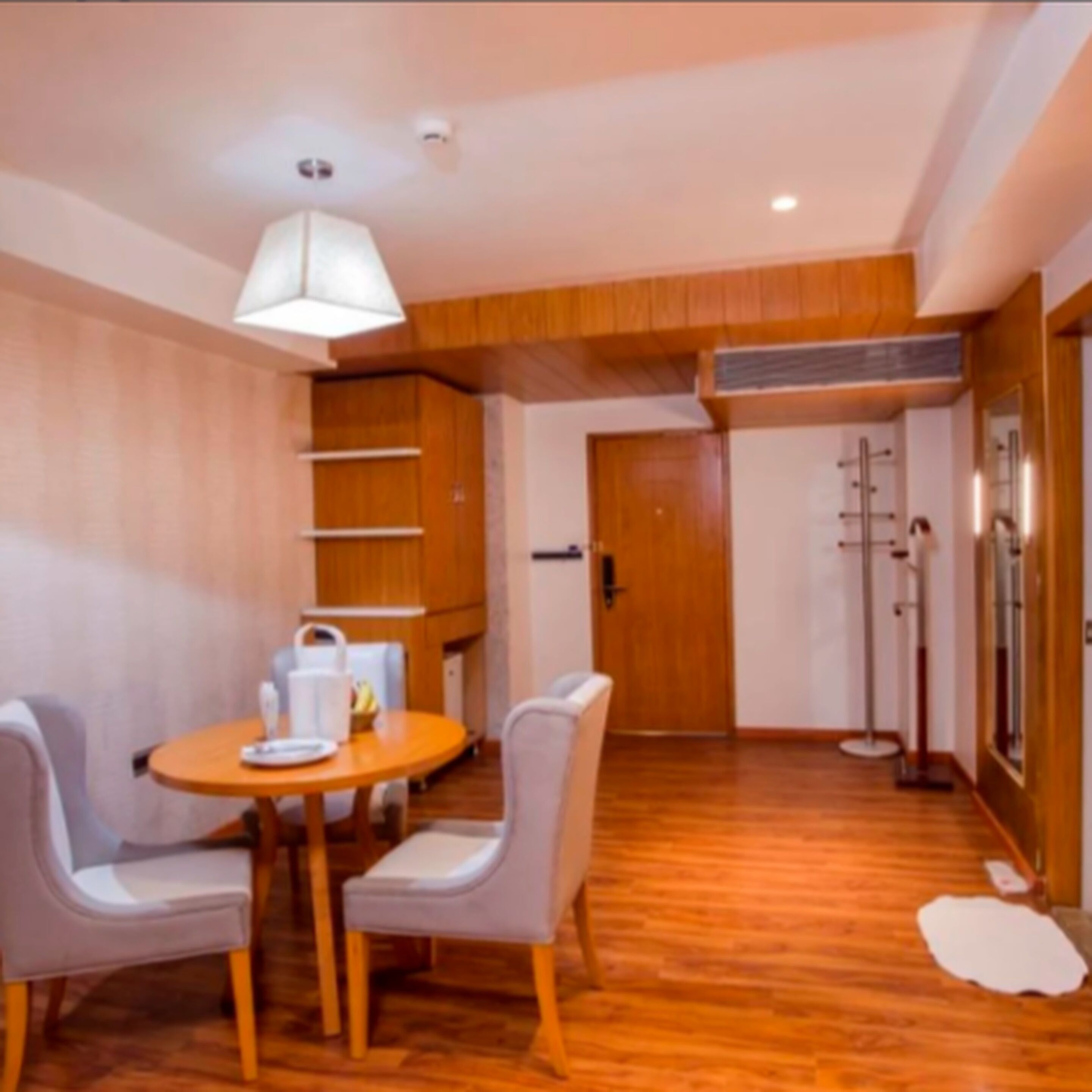 Un espace repas comprenant une table et des chaises en bois, un luminaire suspendu au plafond et un plancher en bois.