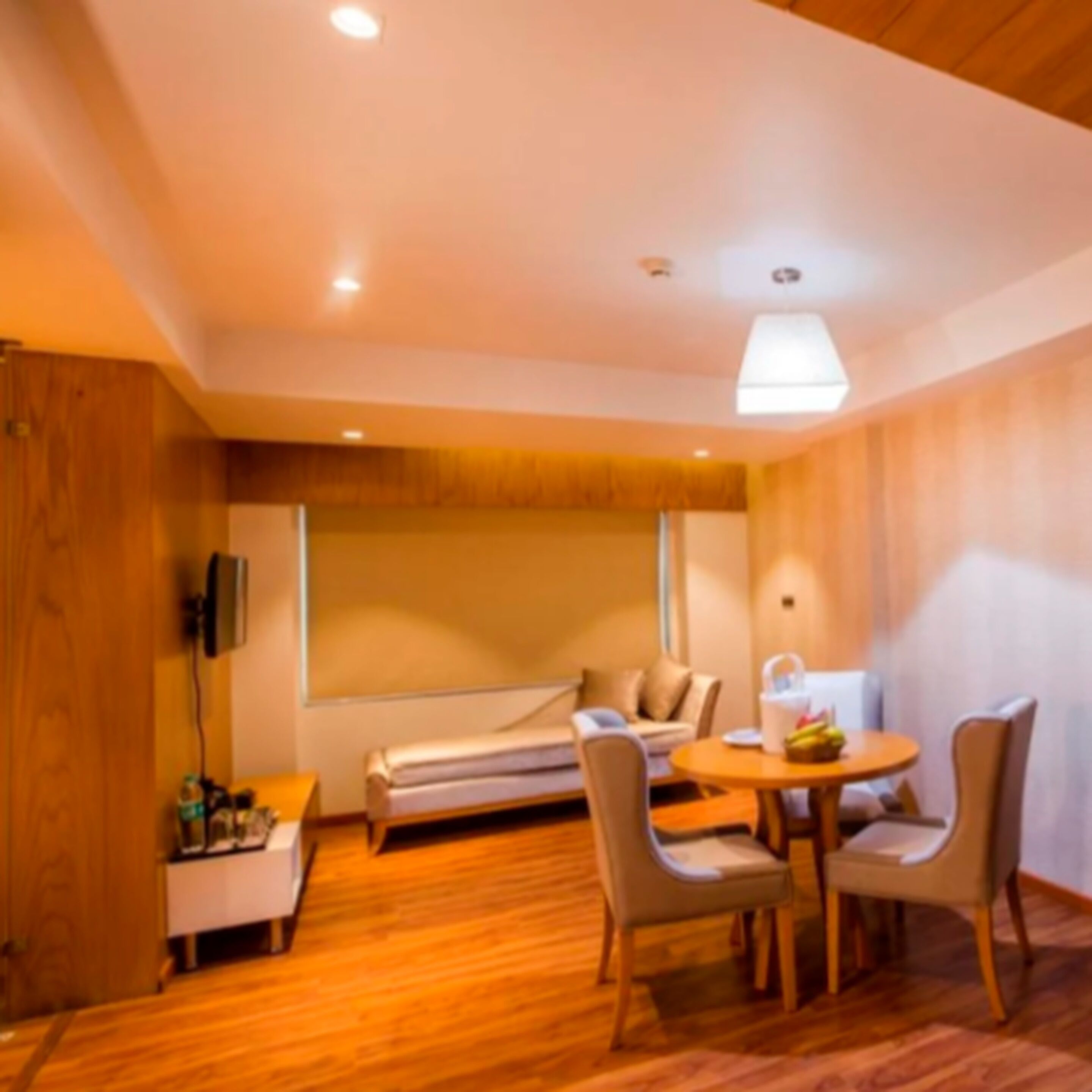 A modern room with a wooden floor, a bed, a sofa, and a dining table with chairs.