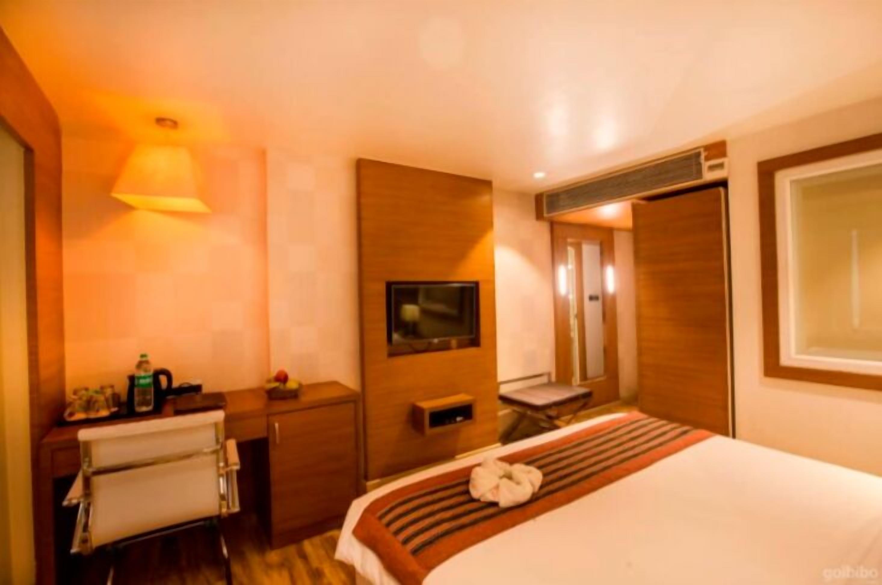 Ein Hotelzimmer mit Bett, Fernseher, Schreibtisch und Spiegel.