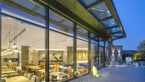 A modern restaurant with a glass facade, outdoor seating, and a stone sculpture. - Holiday Inn Express Suzhou New District by IHG (Suzhou)
