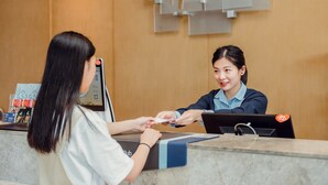 A hotel reception desk with a digital screen, a sign above indicating the hotel name, and a counter with a blue and black design. - Holiday Inn Express Suzhou New District by IHG (Suzhou)