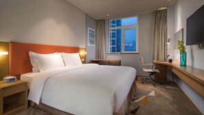 A hotel room with a large bed, a desk, a chair, a TV, and a window with a city view. - Holiday Inn Express Suzhou New District by IHG (Suzhou)