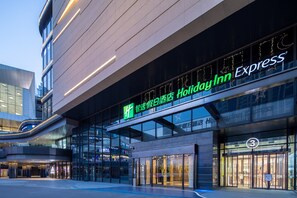 A Holiday Inn Express hotel with a modern glass facade, signage in multiple languages, and a prominent entrance. - Holiday Inn Express Suzhou New District by IHG (Suzhou)