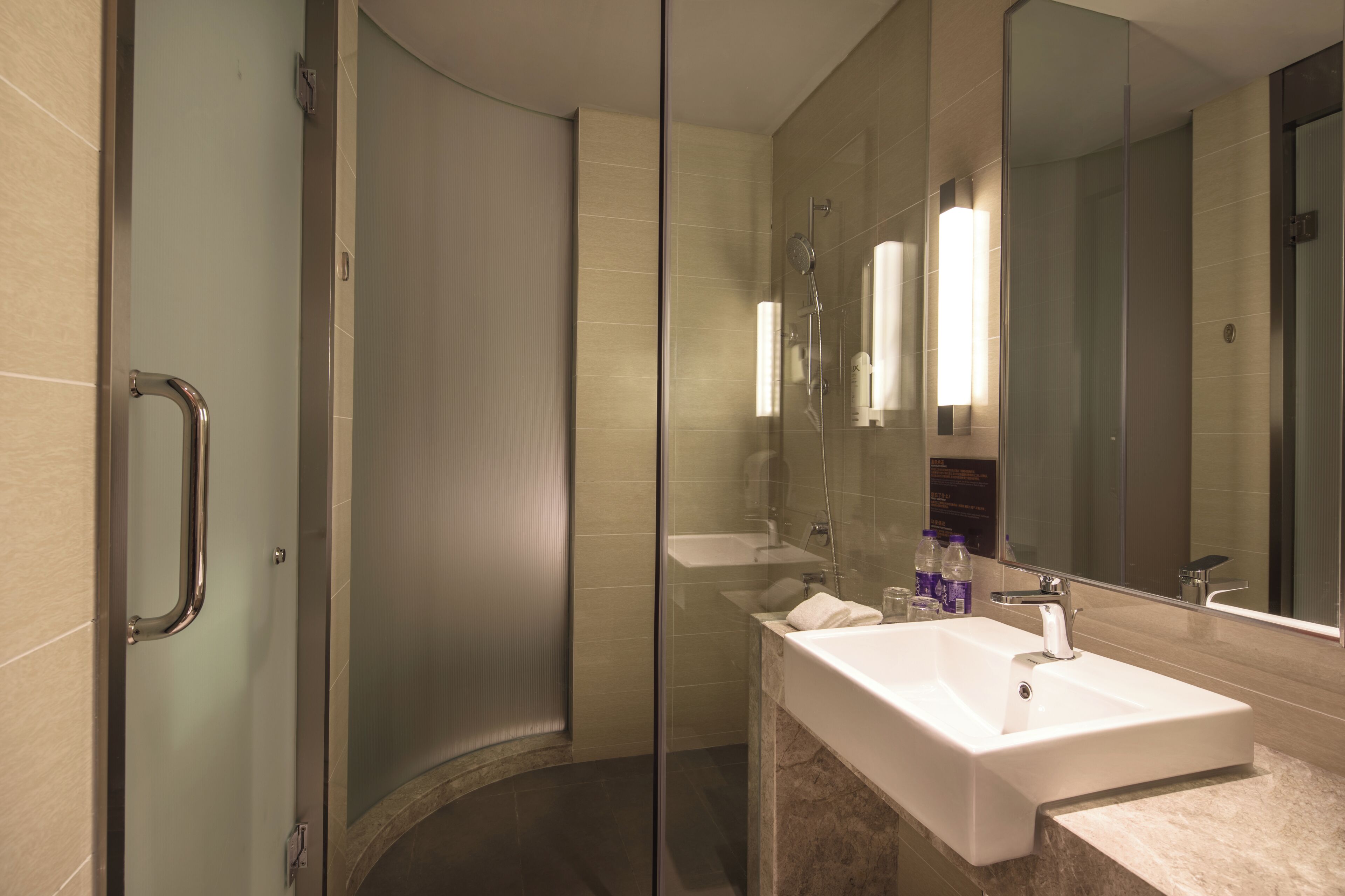 A modern bathroom with a glass shower enclosure, a white sink, and a large mirror.