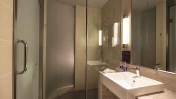 A modern bathroom with a glass shower enclosure, a white sink, and a large mirror.