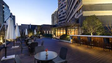 An outdoor patio area with tables and chairs, surrounded by buildings.