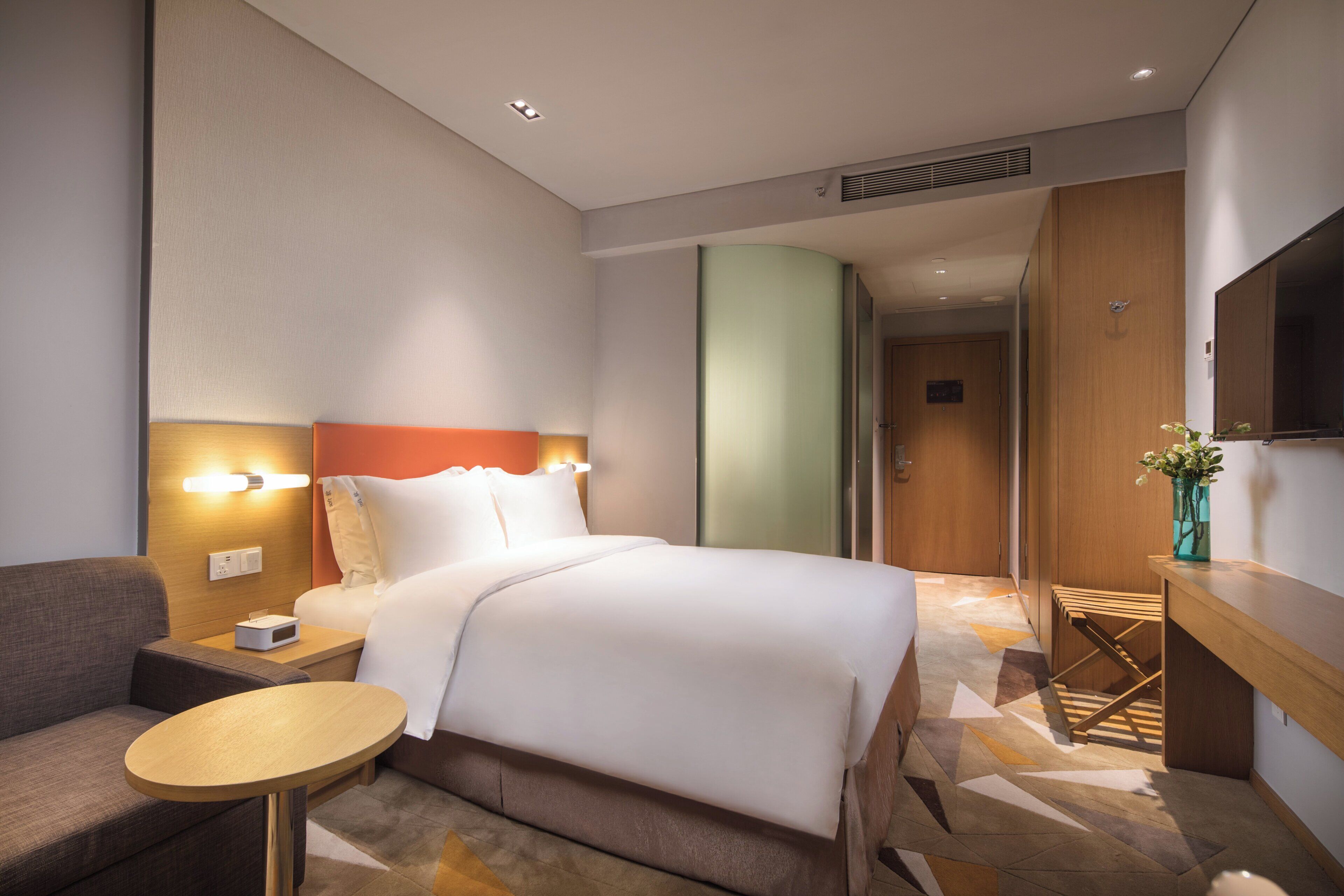 Una habitación de hotel con una cama, un escritorio, una silla, una mesita y un televisor.