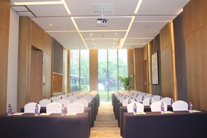 A conference room with rows of chairs and tables, a projector, and large windows with a view of greenery outside. - Holiday Inn Hotel & Suites Tianjin Downtown by IHG (Tianjin)