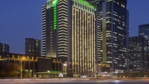 Een hoog hotel met verticale lijnen en verlichte reclameborden, omringd door andere hoge gebouwen.