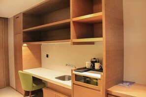 A compact kitchenette with a sink, a green chair, and wooden shelves. - Holiday Inn Hotel & Suites Tianjin Downtown by IHG (Tianjin)