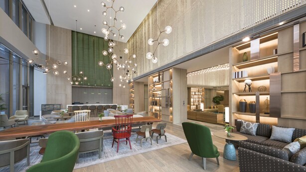 Una hall d'hotel moderna con area bar, posti a sedere e un'ampia finestra che lascia entrare luce naturale.