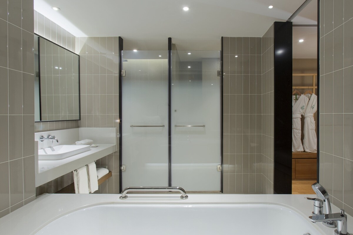 A modern bathroom with a bathtub, a glass shower enclosure, and a vanity with a mirror.