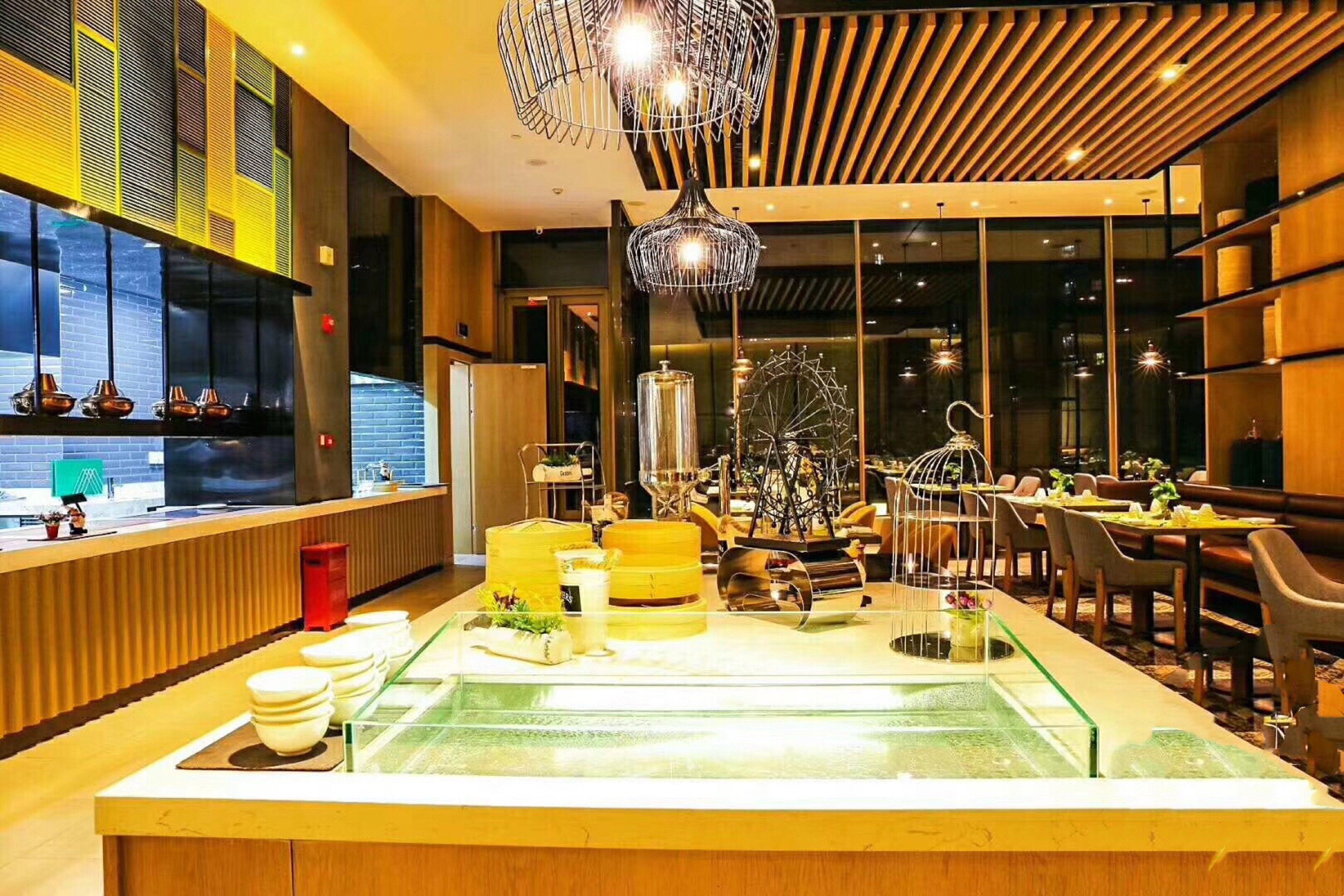 A modern restaurant interior with a central glass display, wooden accents, and a large window.
