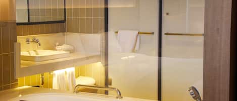 Un baño moderno con un lavamanos grande, un espejo y un separador de vidrio.