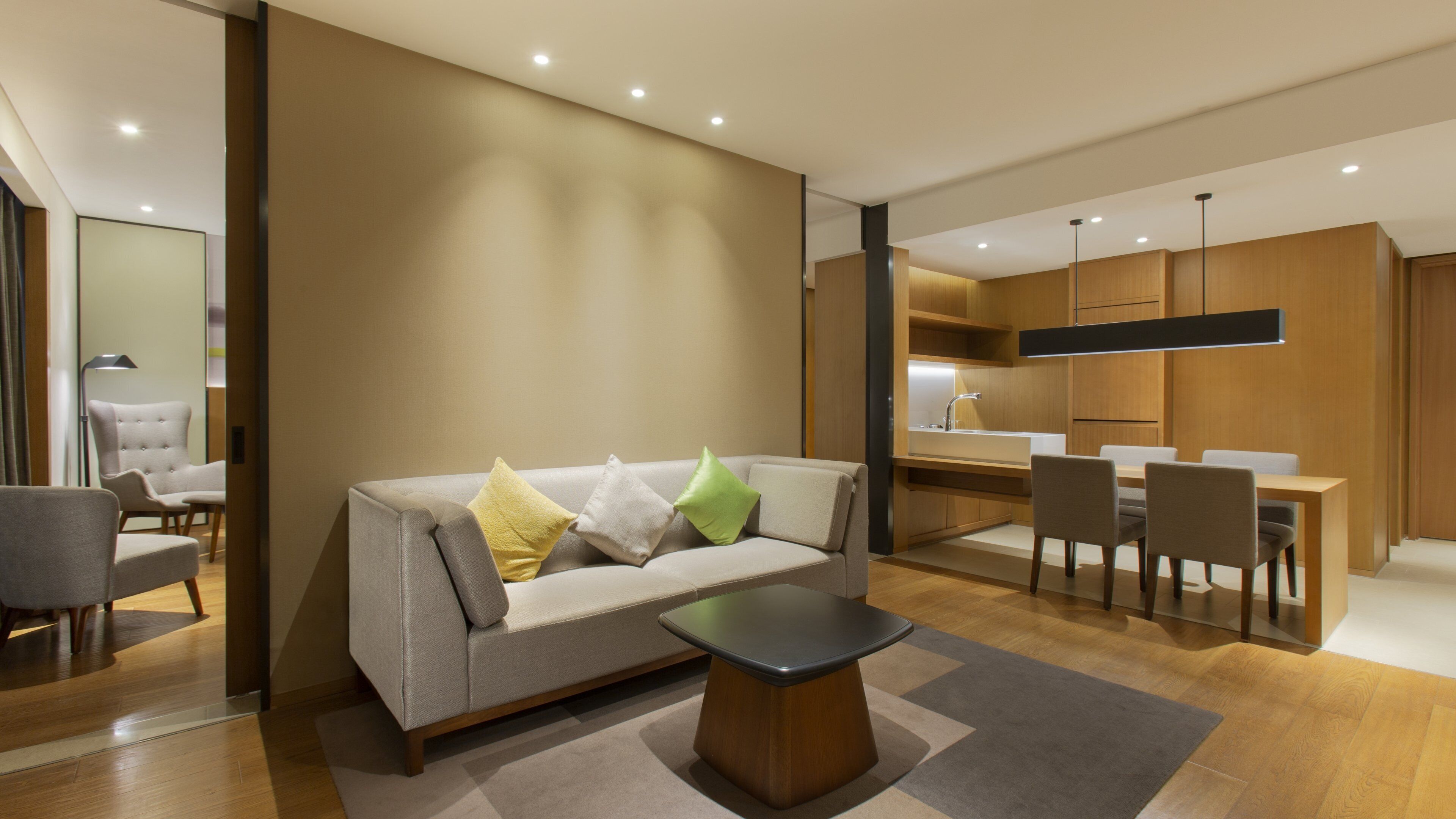 A modern living room with a sofa, a coffee table, and a dining area with chairs and a table.
