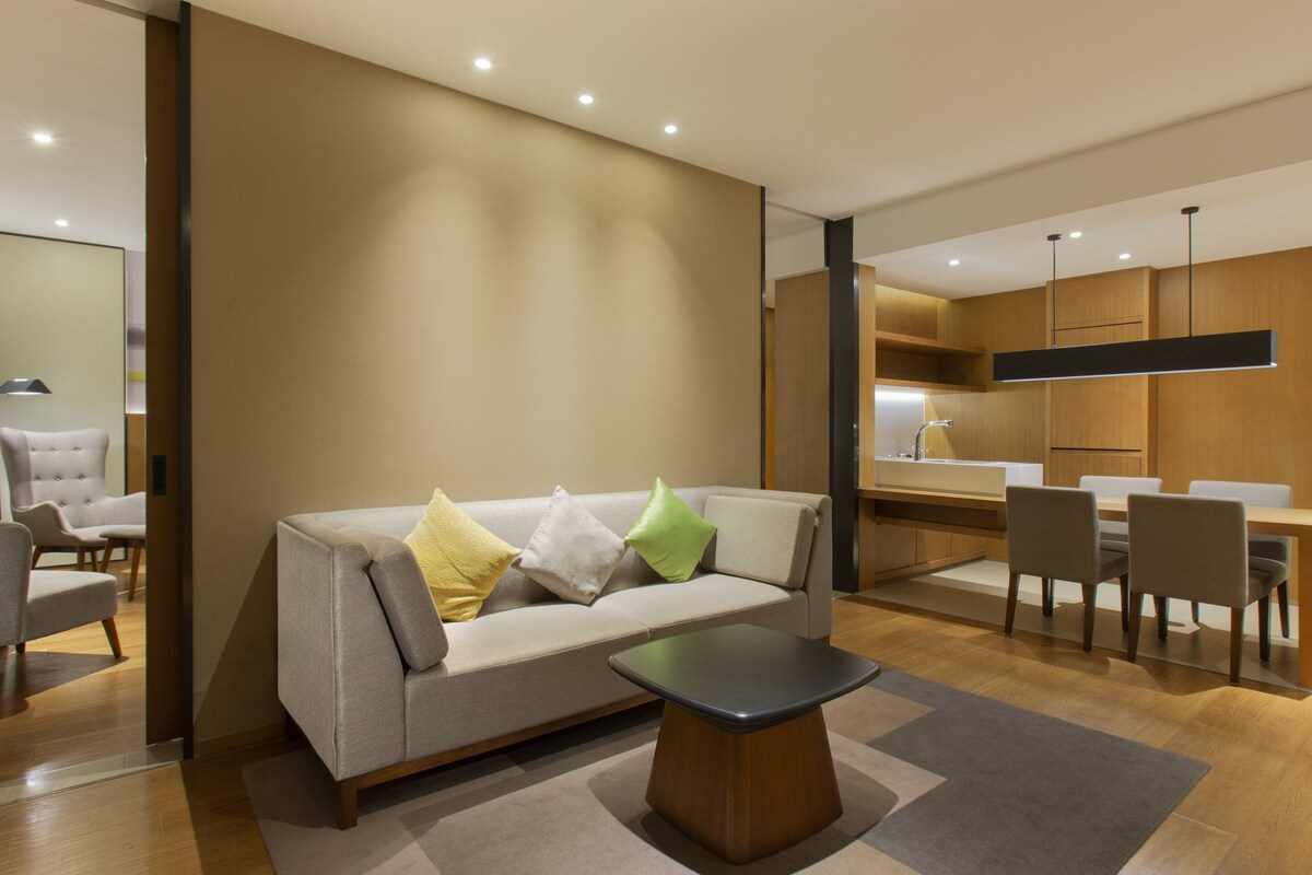 Een moderne woonkamer met een bank, een salontafel, en een eethoek met stoelen en een tafel.