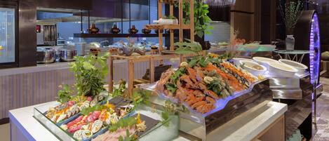 A buffet with various seafood options, including shrimp and sushi, displayed on ice.