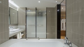 Un bagno moderno con una vasca da bagno ampia, un box doccia in vetro e un mobile lavabo con specchio.