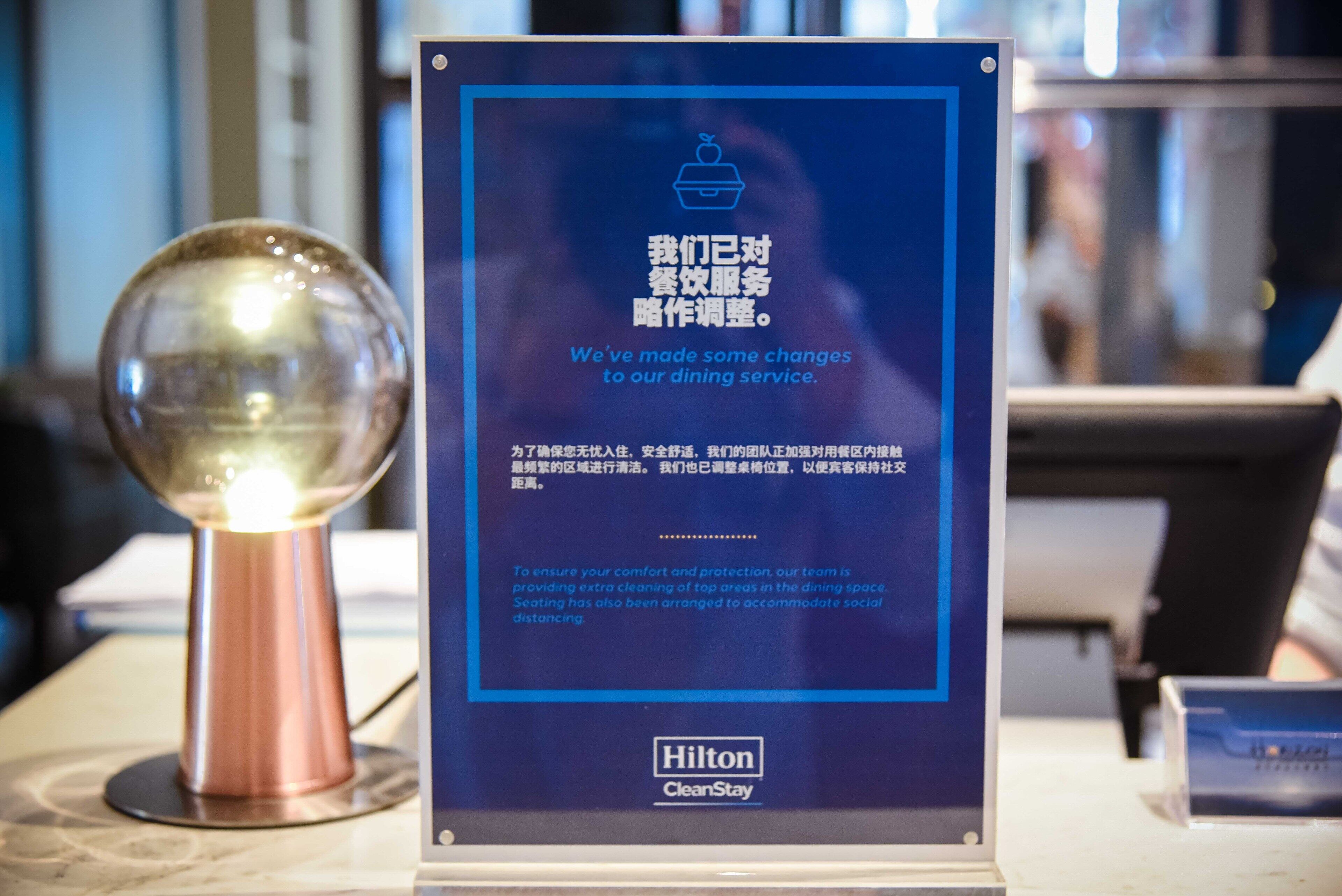 A framed sign with text in both English and Chinese, placed on a table next to a spherical lamp.