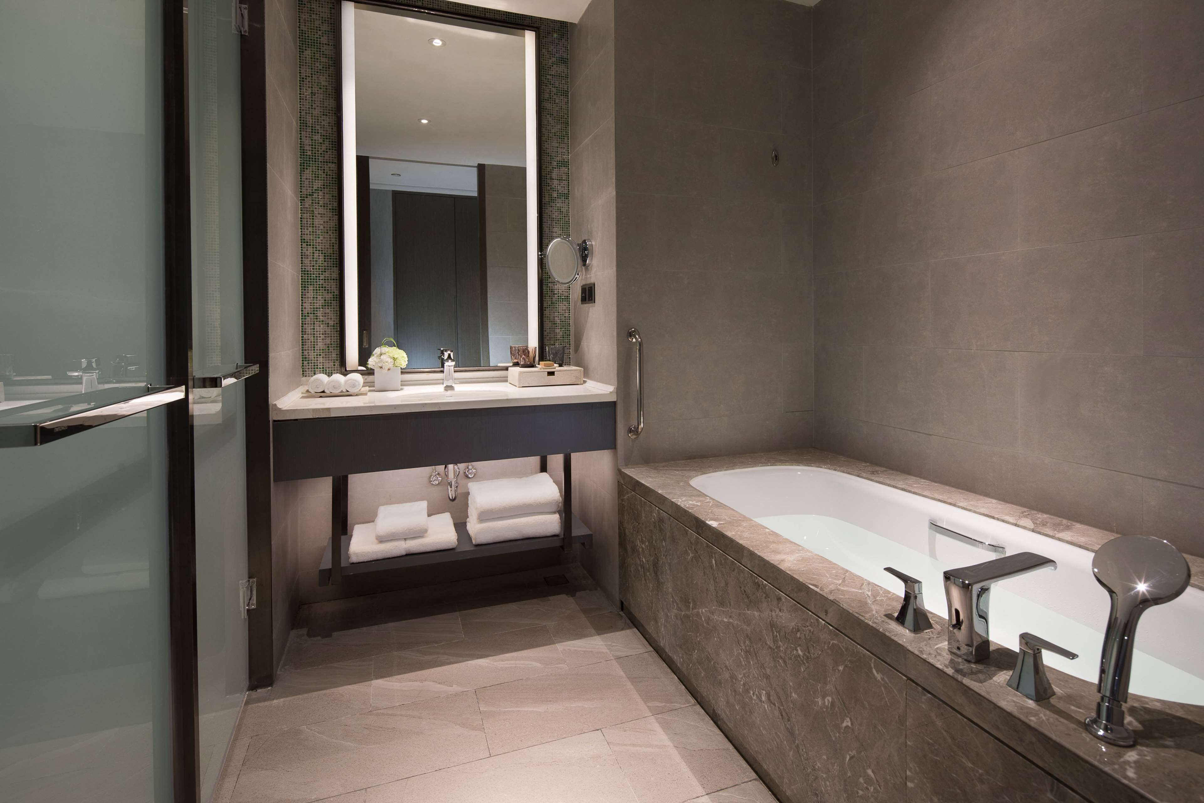 Un baño moderno con cabina de ducha de vidrio, una bañera independiente y un tocador con un espejo grande.