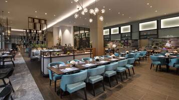 Un restaurante moderno con una mesa común alargada, asientos individuales y una zona de bar.