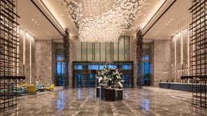 A spacious lobby with a high ceiling, a central floral arrangement, and a reception desk. - DoubleTree by Hilton Qingdao Oriental Movie Metropolis (Qingdao)