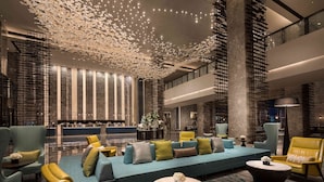 A spacious lobby with a large seating area, a reception desk, and a modern chandelier. - DoubleTree by Hilton Qingdao Oriental Movie Metropolis (Qingdao)