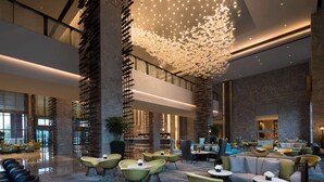 A spacious lobby with multiple seating areas, a large chandelier, and a modern architectural design. - DoubleTree by Hilton Qingdao Oriental Movie Metropolis (Qingdao)