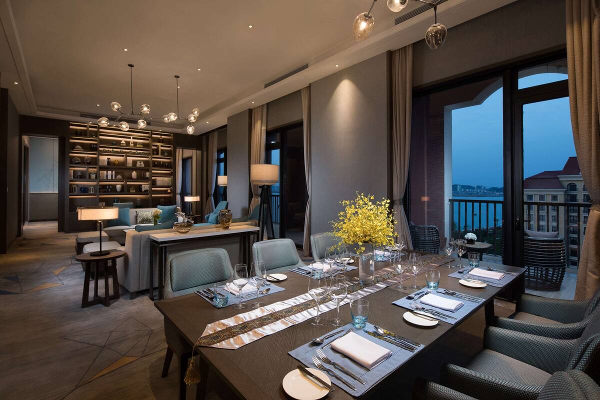 Een moderne eetruimte met een lange tafel gedekt voor een maaltijd, omringd door comfortabele zitplaatsen en een uitzicht op de skyline.