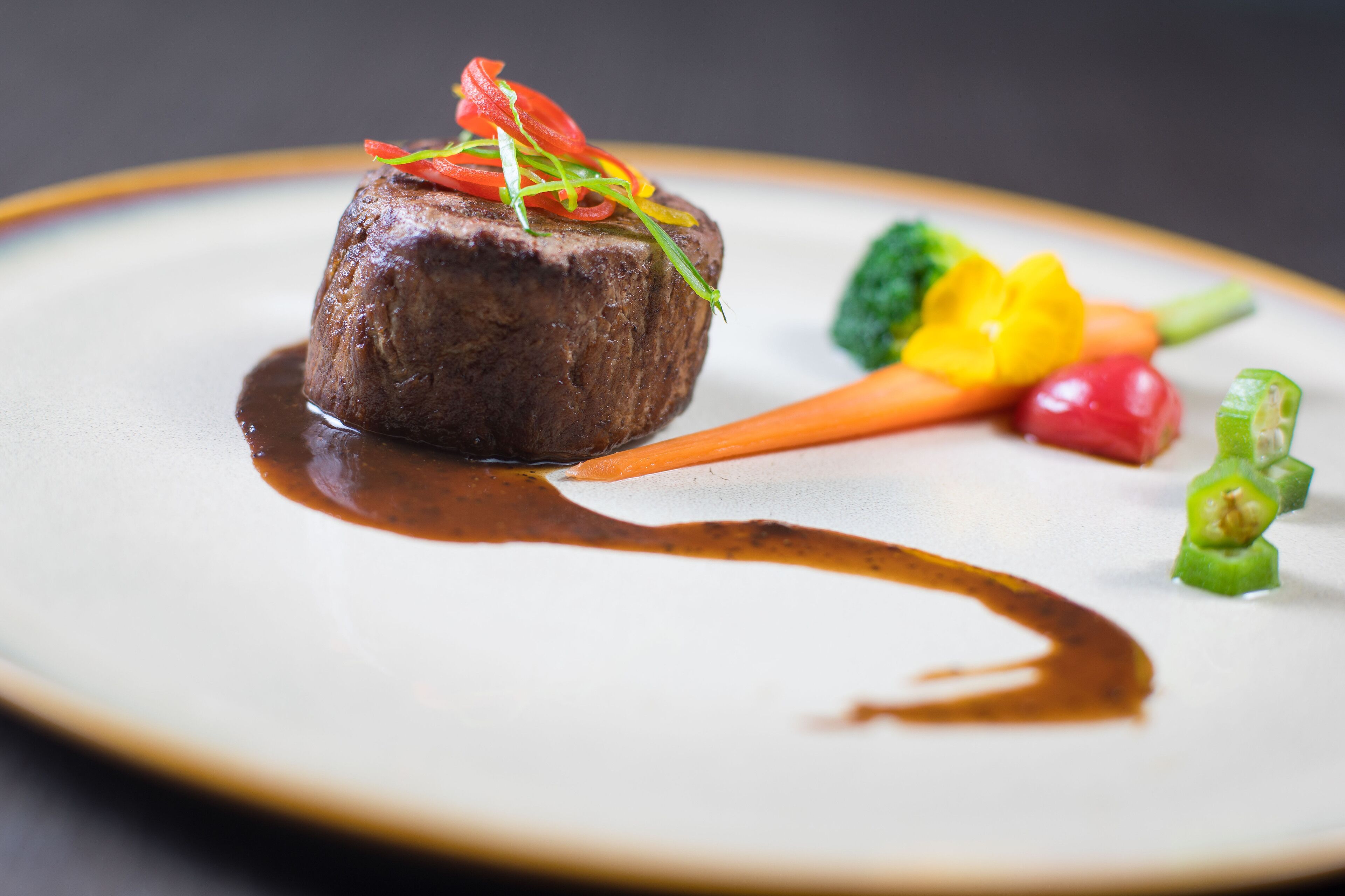 A steak with vegetables and sauce on a plate.