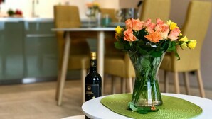 A dining area with a table set for two, a vase with flowers, and a bottle of wine. - Art Suites Spalena (Prague)