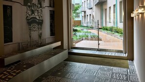 A hotel lobby with a large window offering a view of a courtyard with greenery and a building with balconies. - Art Suites Spalena (Prague)
