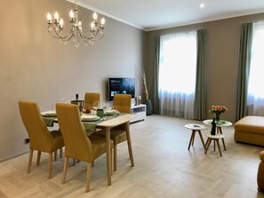A modern dining area with a chandelier, a television, and a seating arrangement. - Art Suites Spalena (Prague)