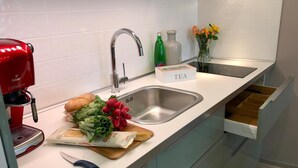 A modern kitchen with a built-in sink, a red coffee machine, fresh vegetables, and a tea sign. - Art Suites Spalena (Prague)