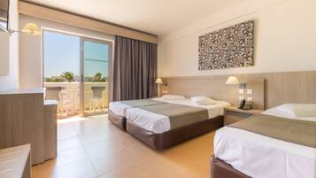 A hotel room with two beds, a desk, and a balcony with a view of the city.