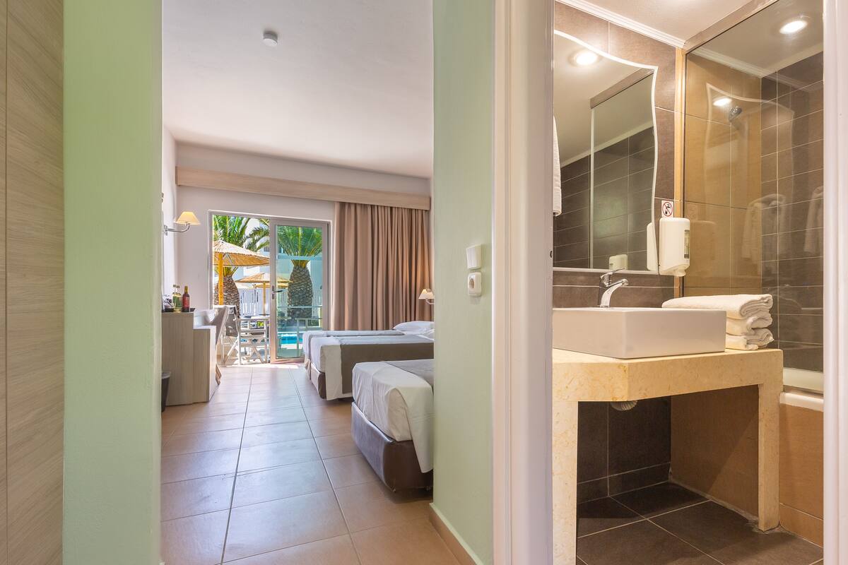 A hotel room with a bathroom, a balcony, and a view of the outdoors.