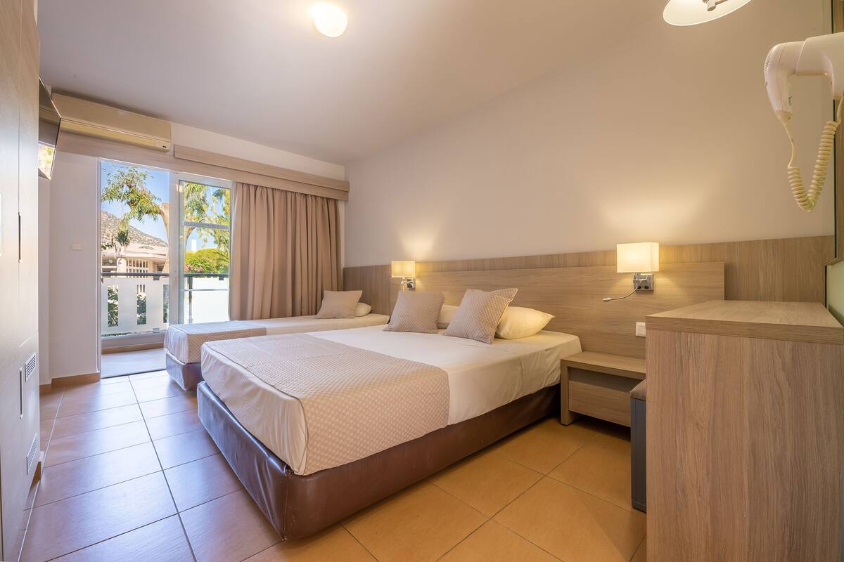A hotel room with two beds, a desk, a lamp, and a hairdryer.
