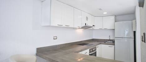 A modern kitchen with white cabinets, a wooden countertop, and built-in appliances.