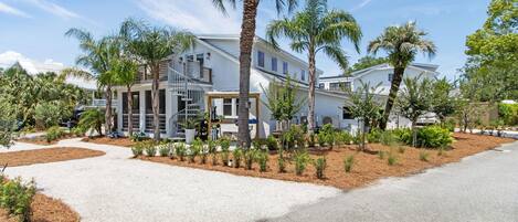 Et moderne hotel med en central trappe, palmer og en velholdt have.