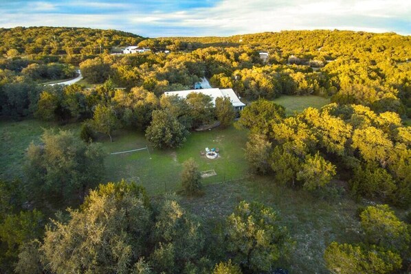 Vista aérea de una propiedad rural con una casa grande rodeada de bosque denso.