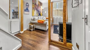 Ein modernes Wohnzimmer mit Holzboden, einem weißen Sofa, einem kleinen Tisch und einem Bild an der Wand.